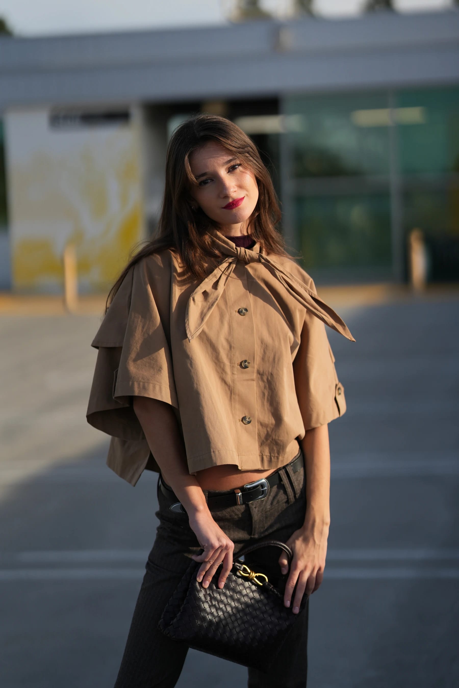 Rosina half body holding a woven bag in front of a modern building — photo A