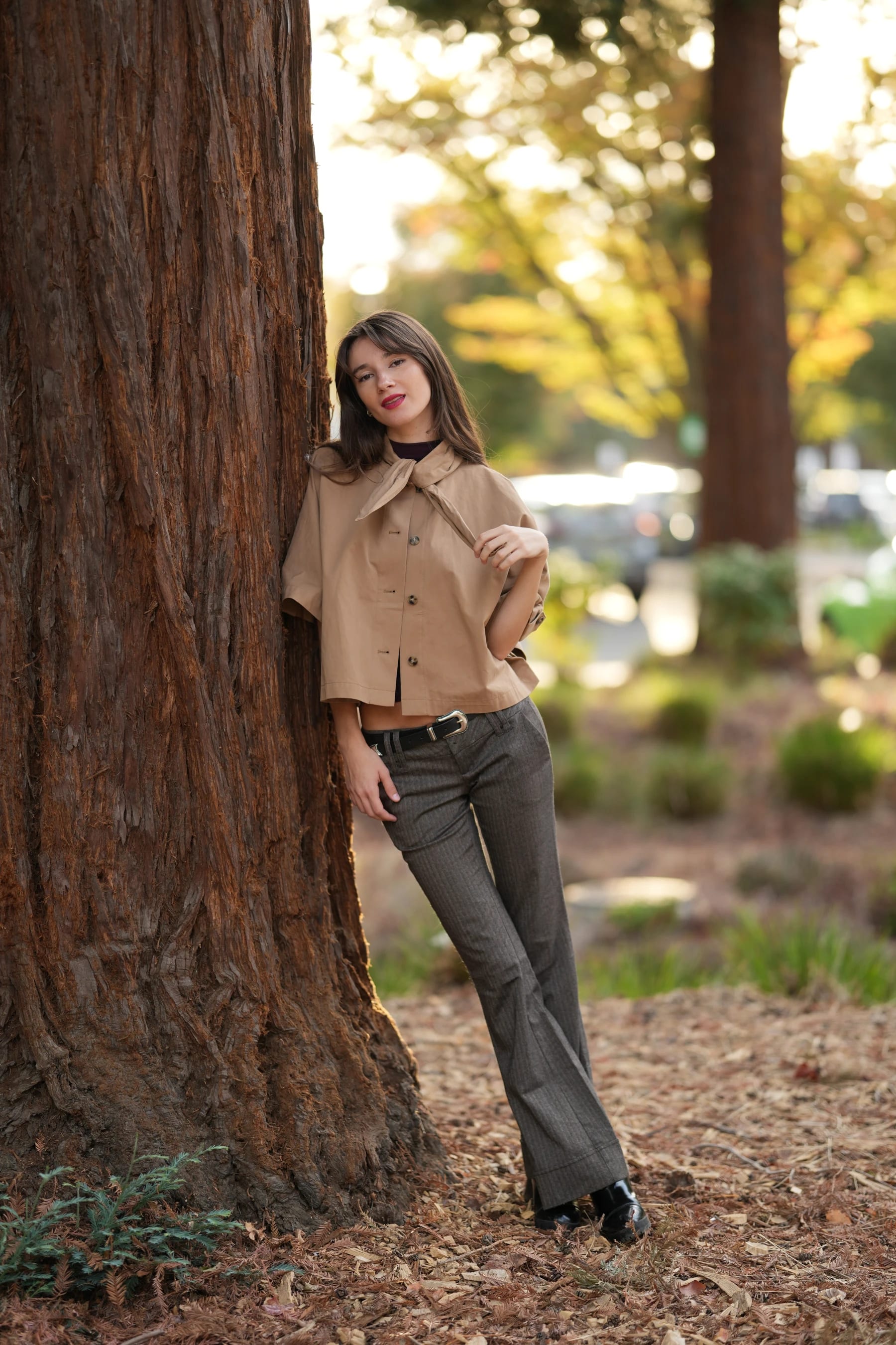 Rosina full length leaning against a redwood — photo A