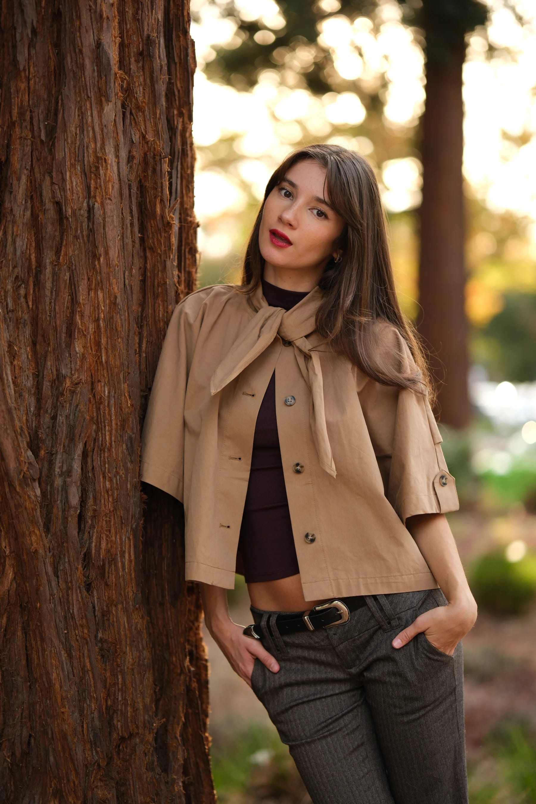 Rosina leaning on a redwood trunk with her hands in her pockets — photo A