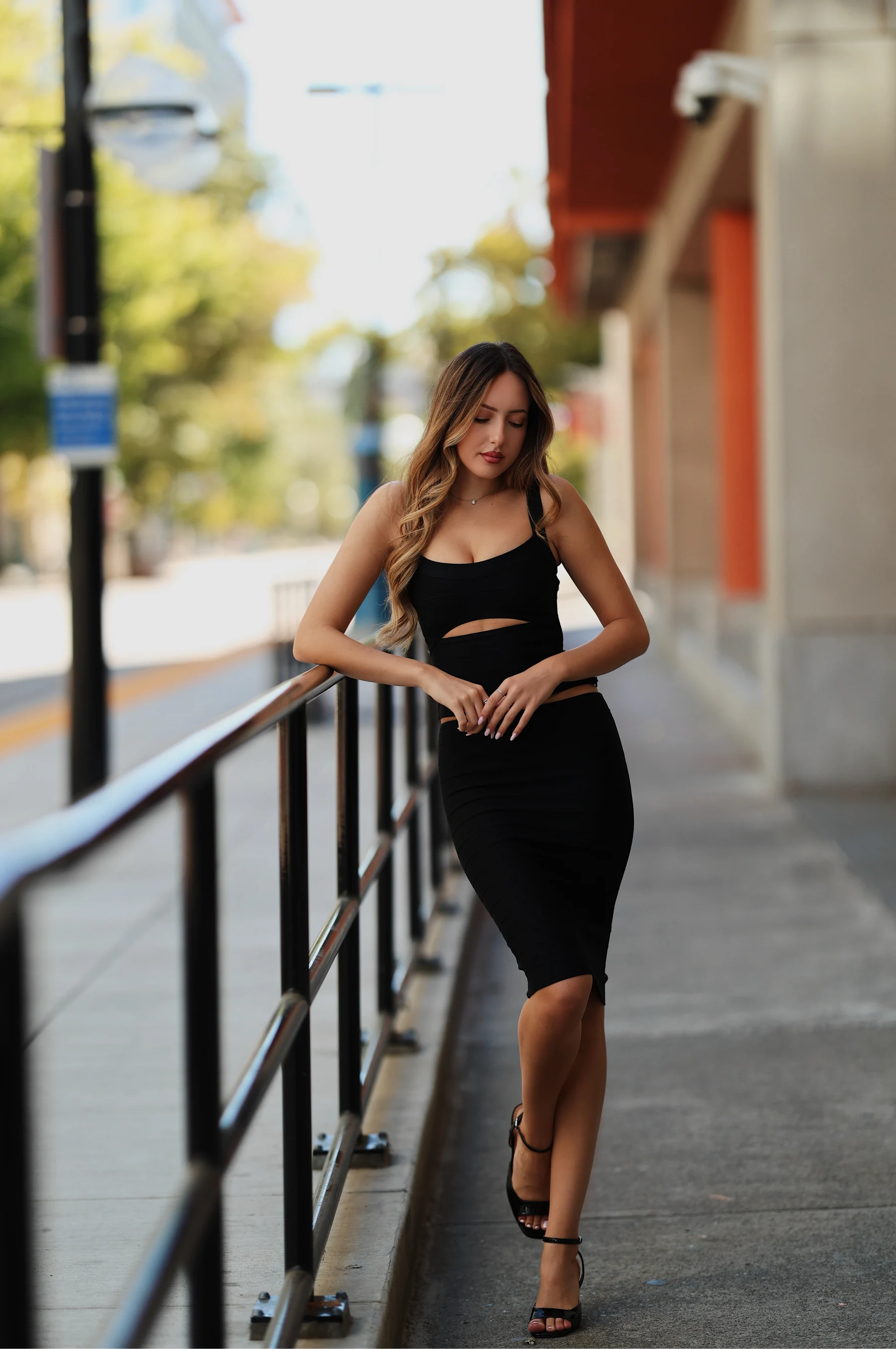 Andrea at a light rail platform, leading line composition, all-black outfit 1 of 4