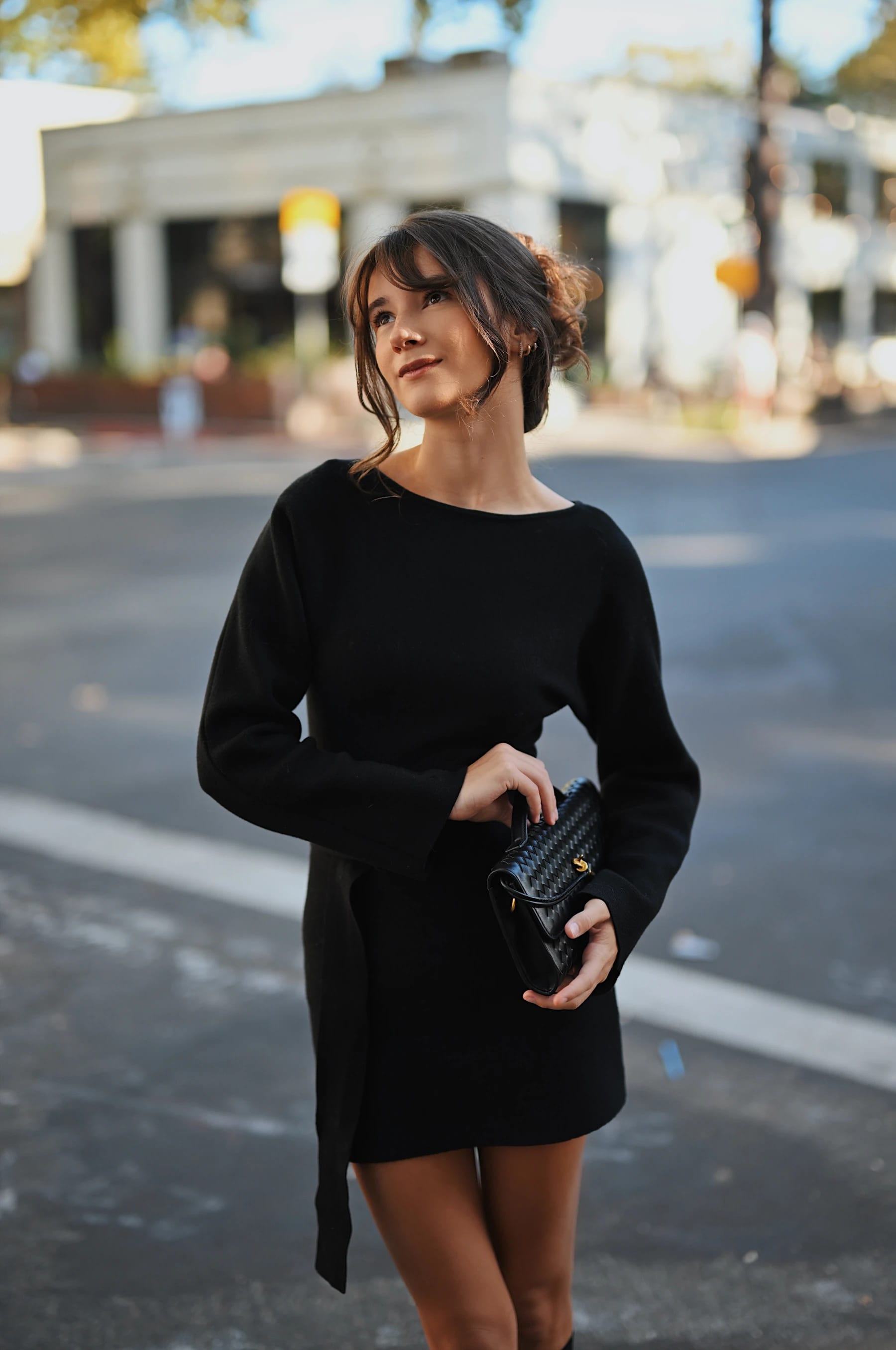 Rosina street portraits at an intersection with a white building and string-light bokeh 1 of 8