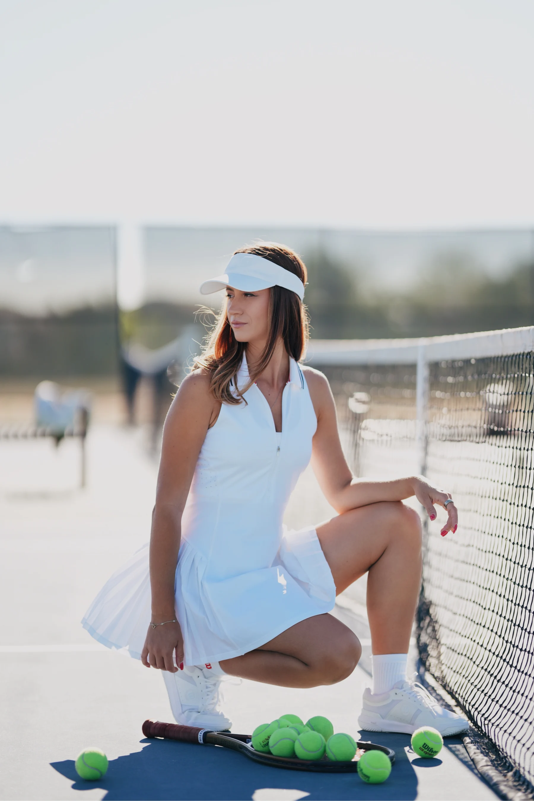 Natalia crouched courtside in green tennis skirt, gathering tennis balls 1 of 6