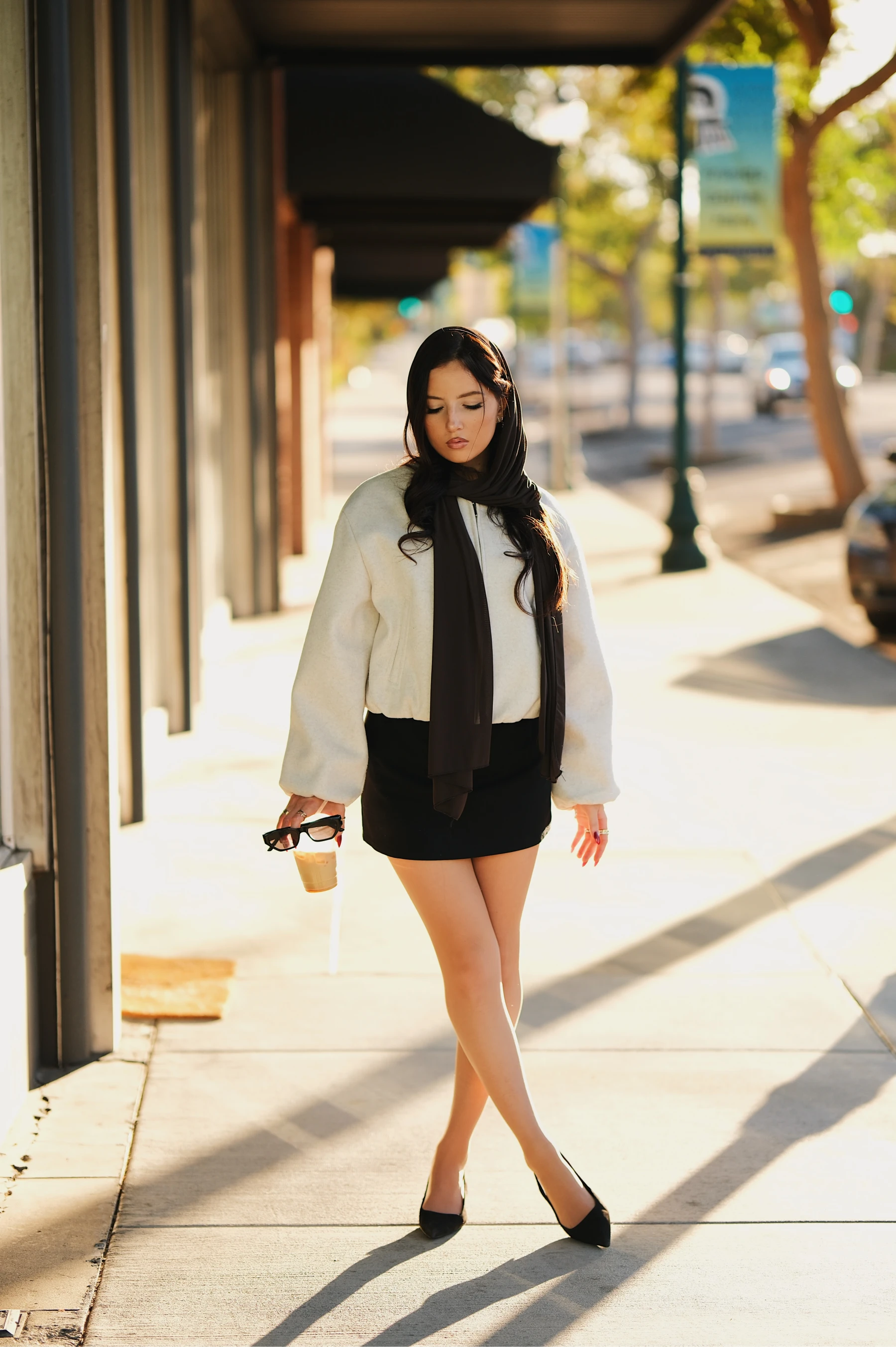 Yasmina walking under storefront awnings with long diagonal shadows, full body on the Fujifilm X-H2